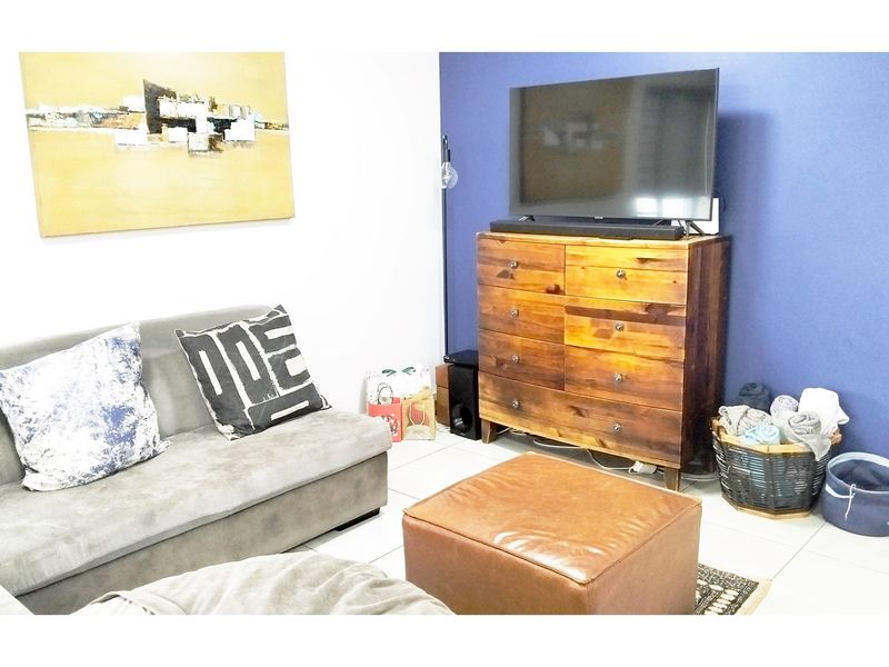 A living room featuring tiled flooring and a blue accent wall, providing a functional space for relaxation.