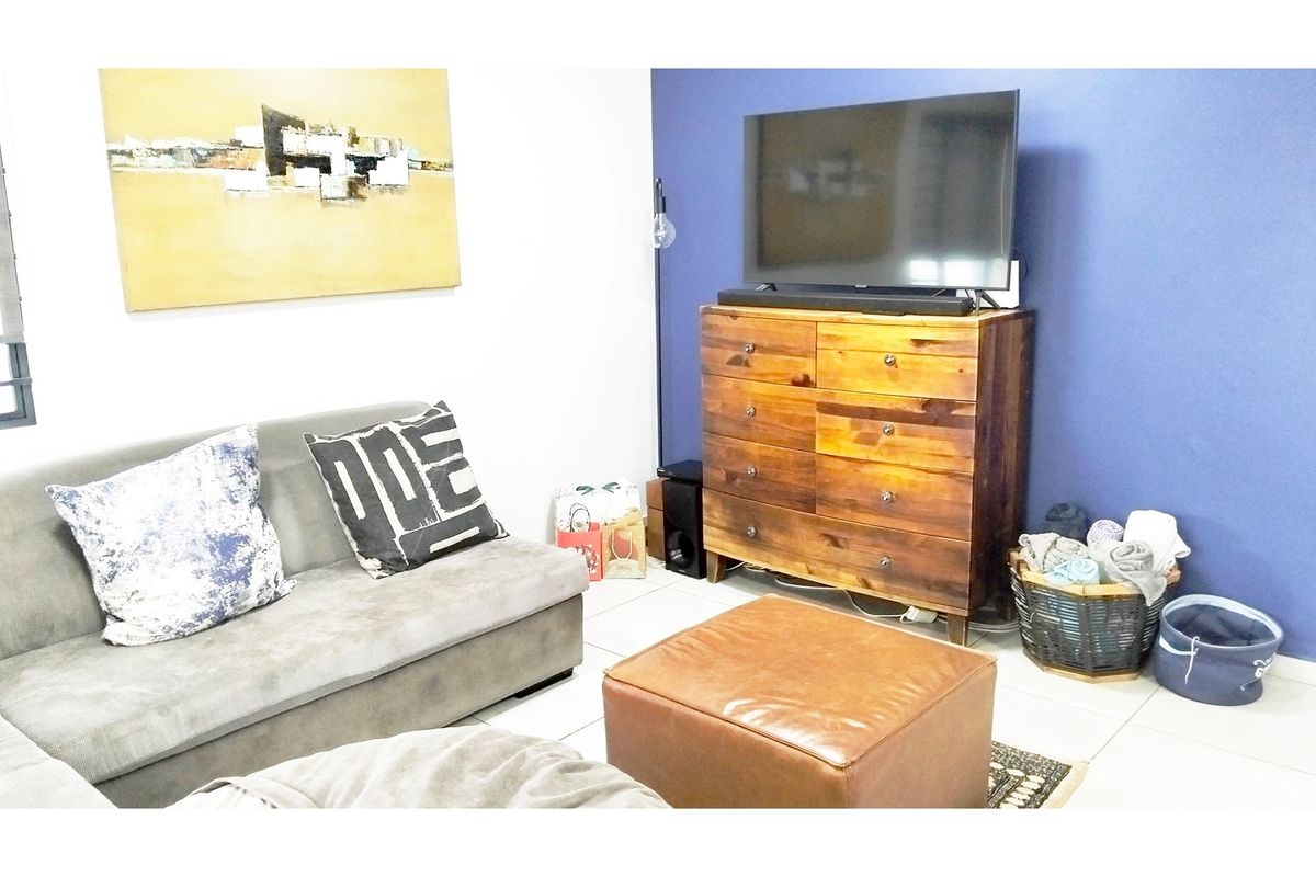 A living room featuring tiled flooring and a blue accent wall, providing a functional space for relaxation.