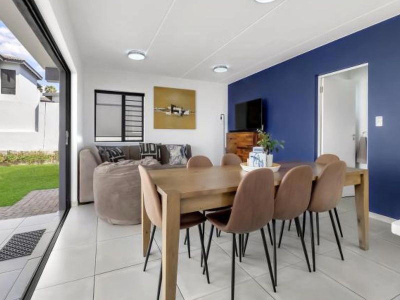 Bright open-plan living and dining area featuring large sliding glass doors that provide seamless access to the outdoor garden space.