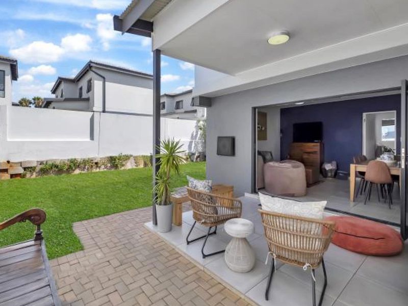 A covered patio area featuring tiled flooring and bi-fold doors that provide seamless access to the open-plan living space and rear garden.