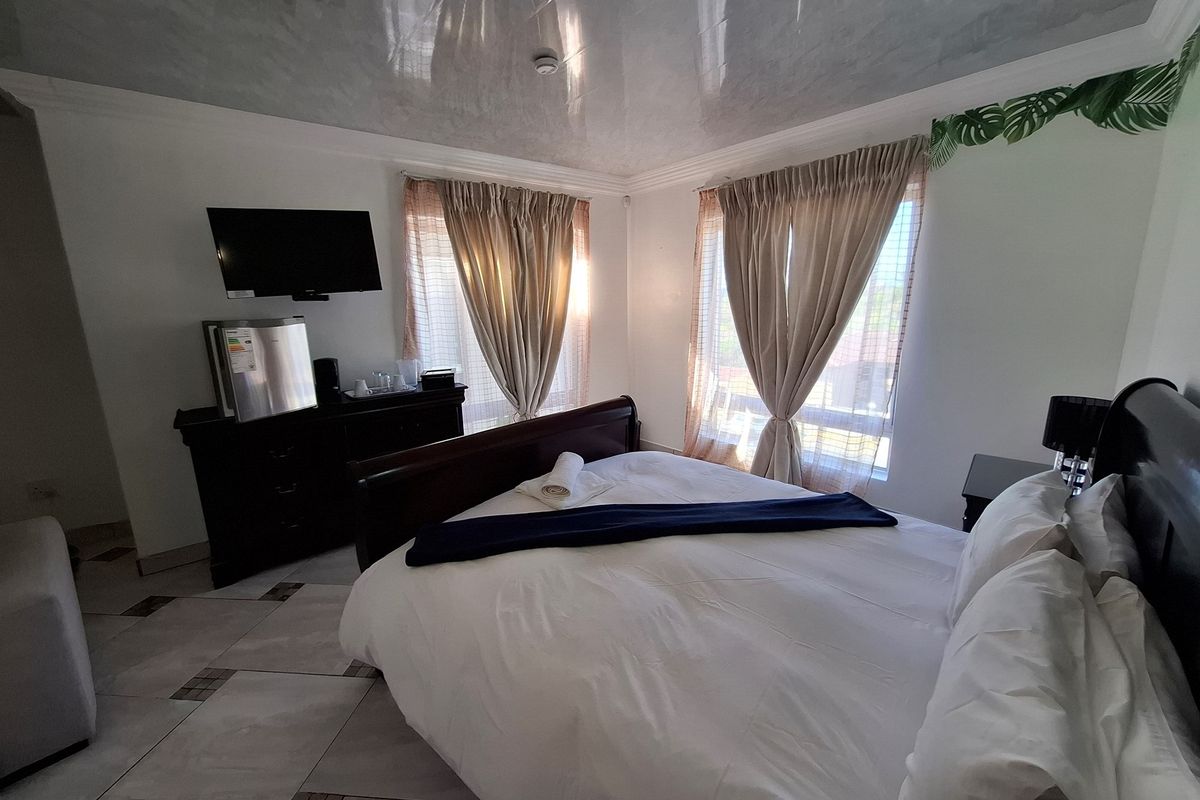 A bedroom featuring tiled flooring and a glossy ceiling finish, illuminated by natural light from dual windows.