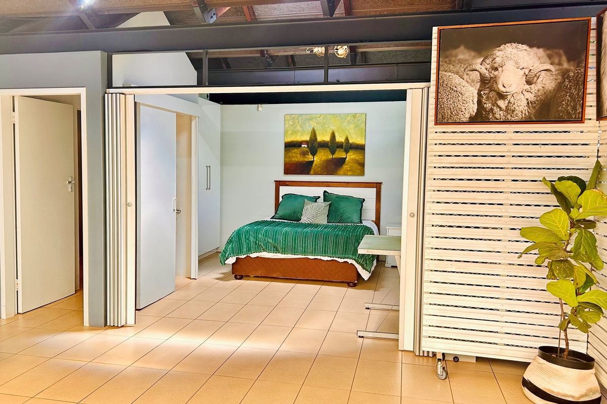 A bedroom featuring tiled flooring, built-in cupboards, and a folding partition door, set under an exposed industrial-style ceiling.