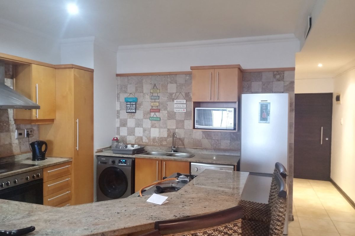 A functional kitchen featuring light wood cabinetry, granite countertops, a breakfast bar, and integrated appliances, including a built-in oven and extractor fan.