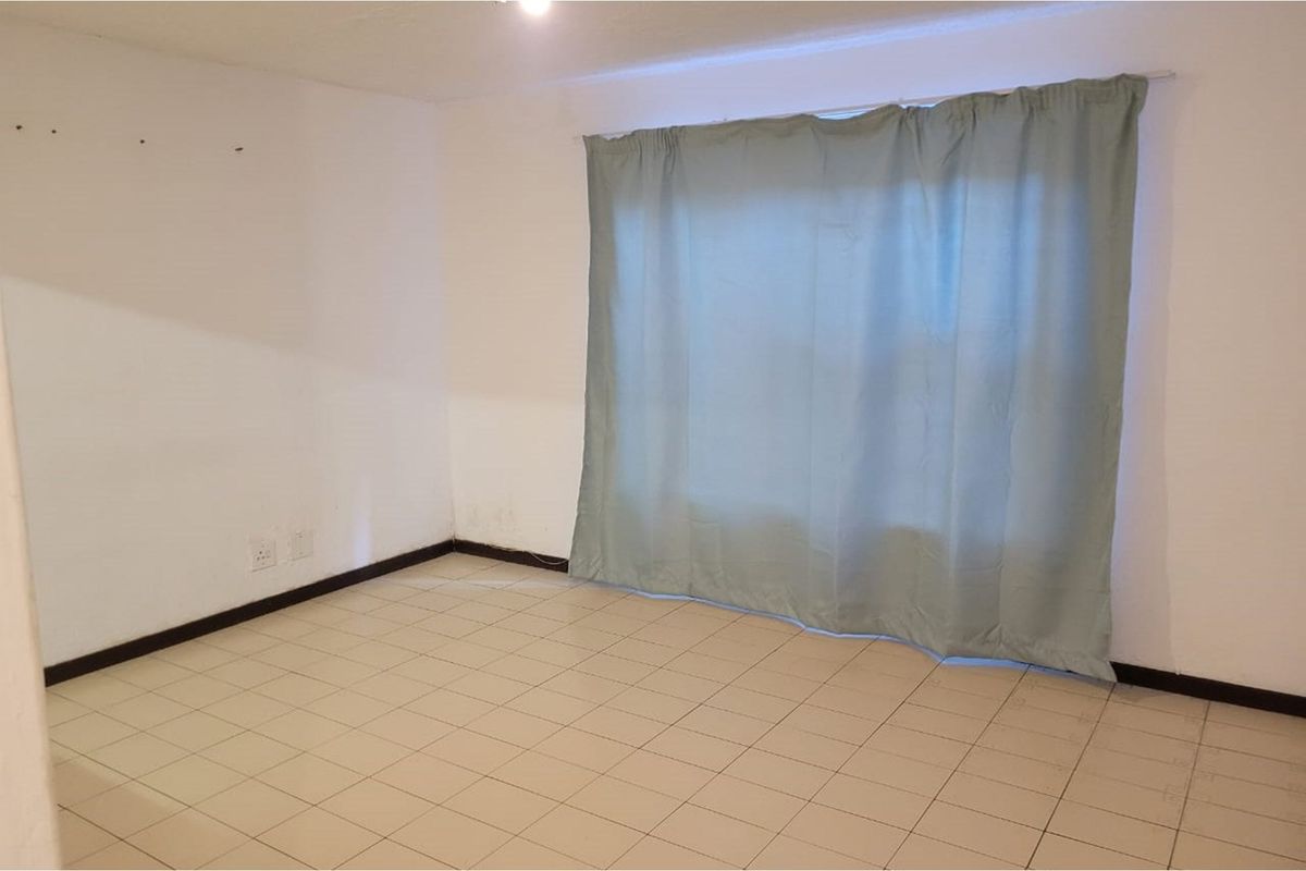 An empty living room featuring tiled flooring and neutral walls, providing a blank canvas for personalization and interior design updates.