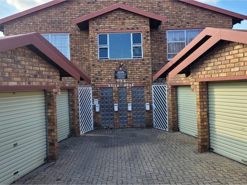 Front elevation of the Villa Nova apartment complex featuring face brick construction, multiple garage units, and a paved driveway entrance.