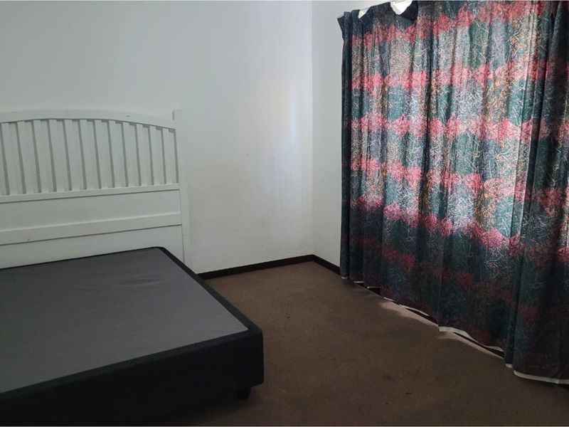 A bedroom featuring carpeted flooring and full-length window curtains, offering a blank canvas for potential interior updates and modernization.