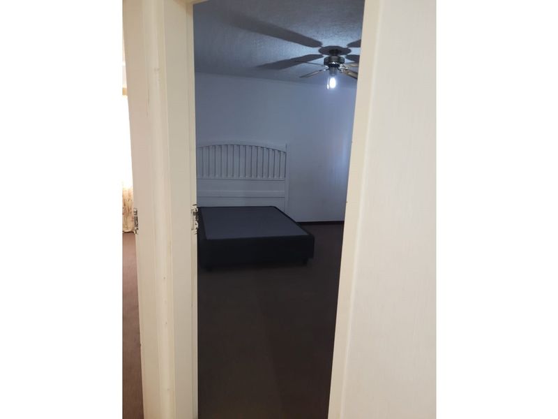 A bedroom featuring a ceiling fan, viewed through an open doorway.