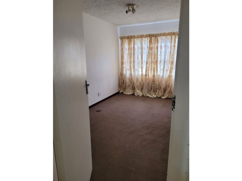 An empty bedroom featuring carpet flooring and a ceiling light fixture, ready for renovation or staging.