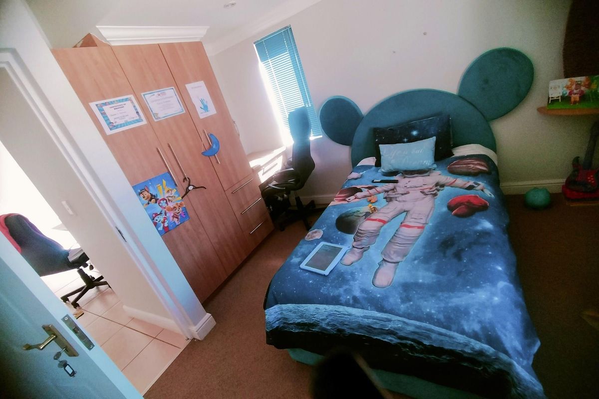 A bedroom featuring built-in wooden cabinetry and carpeted flooring, with a window providing natural light.