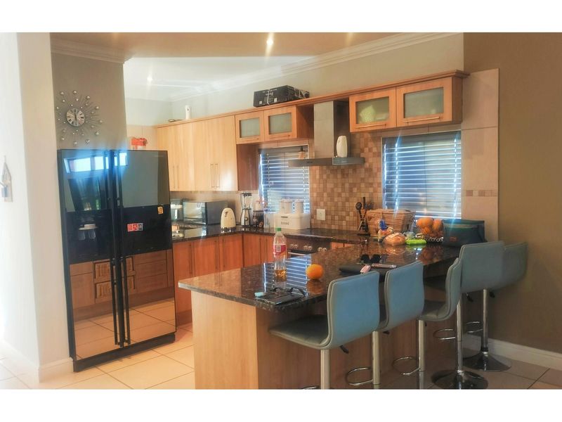 A functional kitchen featuring wooden cabinetry, granite countertops, a breakfast bar, and built-in stainless steel appliances including an extractor fan.