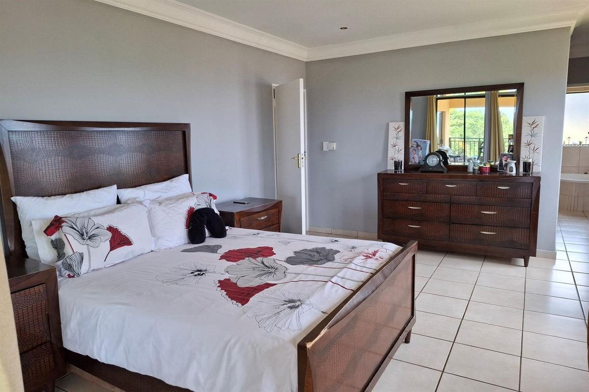Spacious bedroom featuring tiled flooring, crown molding, and direct access to an en-suite bathroom area.