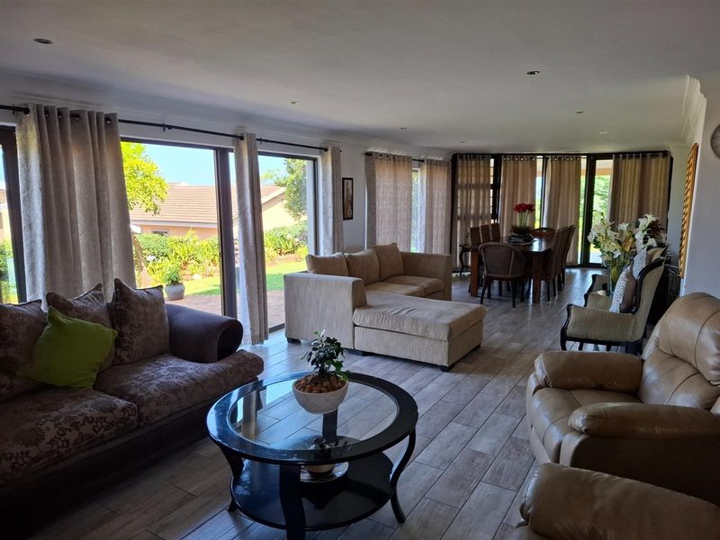 Spacious open-plan living and dining area featuring large sliding glass doors that provide seamless access to the outdoor patio and garden.