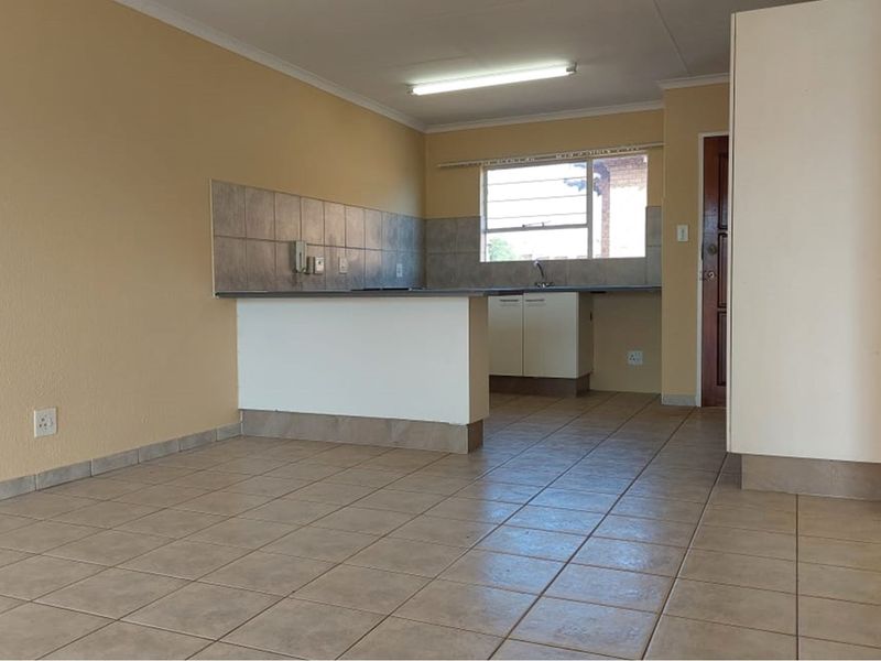 An empty kitchen featuring tiled flooring, built-in cabinetry, and a tiled splashback, offering a functional space ready for modernization.