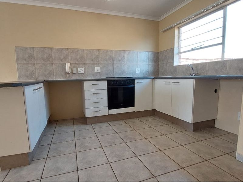 A functional kitchen featuring white cabinetry, laminate countertops, tiled backsplash, and a built-in oven with hob, offering a clean and practical workspace.