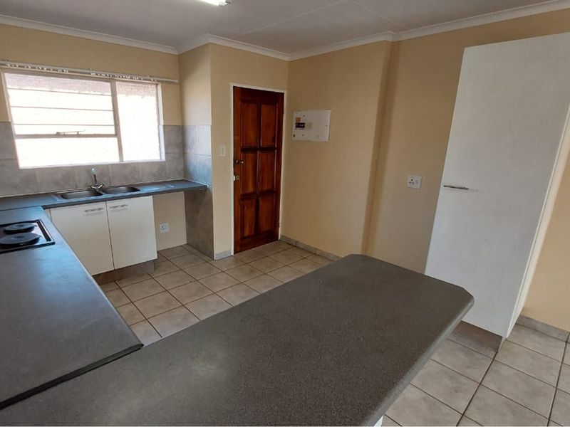 A functional kitchen featuring tiled flooring, built-in cabinetry, laminate countertops, an electric hob, and a convenient built-in pantry cupboard.