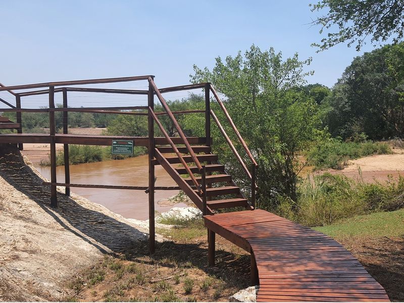 A well-maintained wooden boardwalk and staircase providing access to the riverfront area, offering scenic views of the natural landscape.