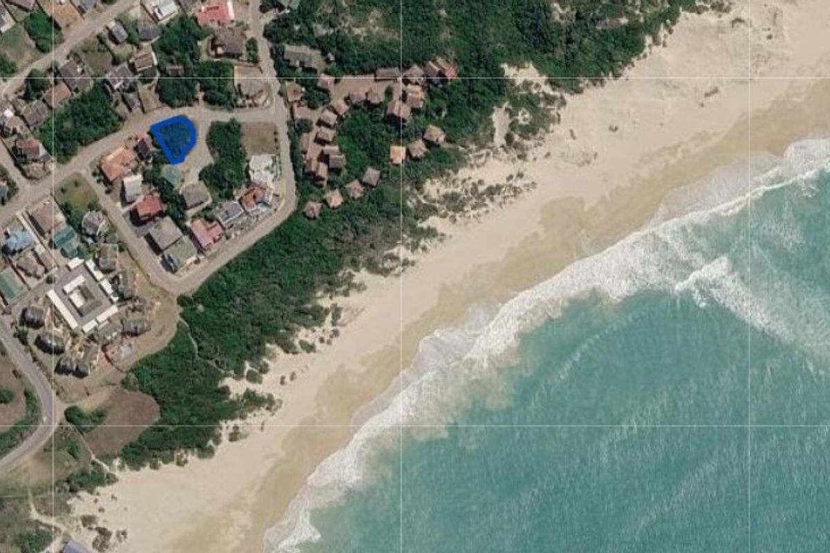 Aerial view of a residential land plot situated in a coastal neighborhood with direct proximity to the beach.