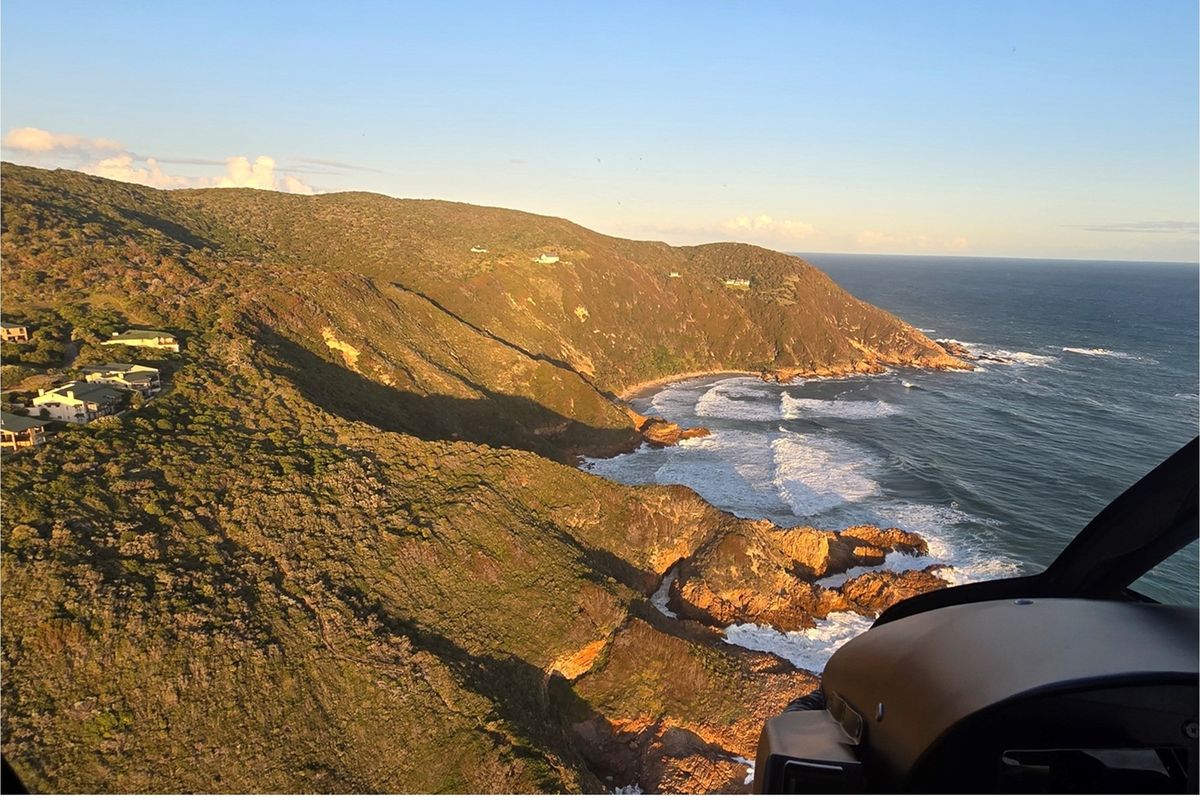 An aerial view of the coastal landscape, showcasing the rugged coastline, ocean waves, and surrounding natural terrain.