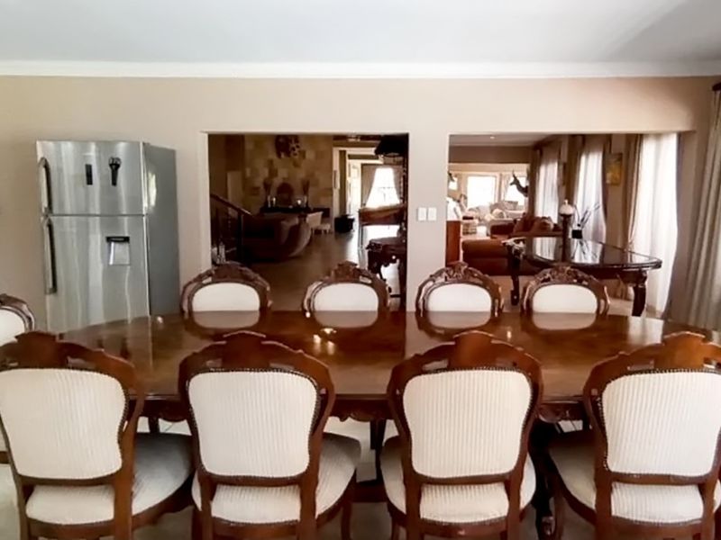 Spacious open-plan dining area featuring a large wooden table and views through to the adjacent living spaces.