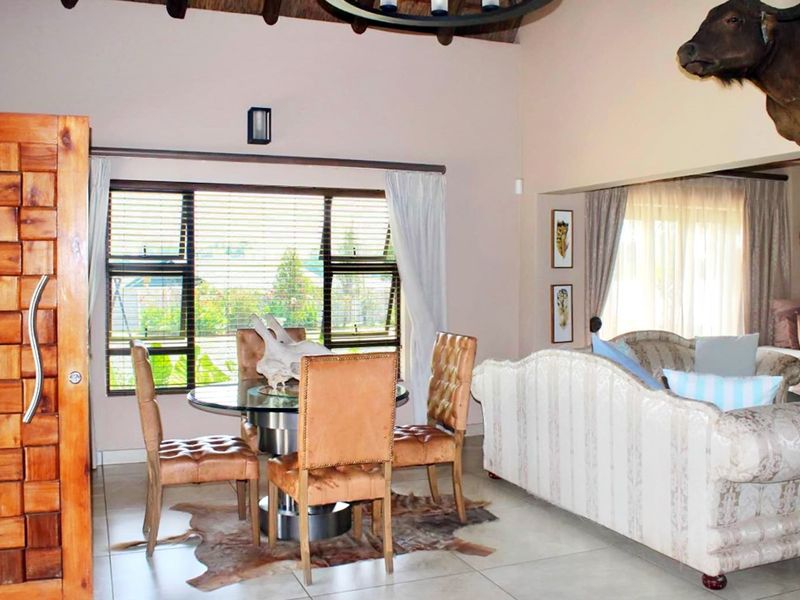 Open plan living and dining area featuring high vaulted ceilings with exposed timber beams and large windows allowing for natural light.
