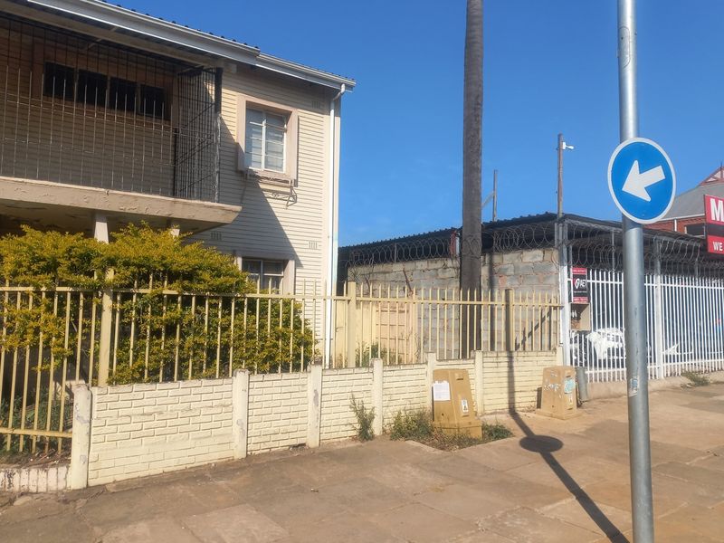 Street view of the apartment building exterior featuring a security-fenced boundary wall and balcony with security bars.