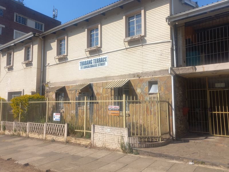 Front elevation of Thabang Terrace apartment building featuring stone cladding, weatherboard siding, and secure metal perimeter fencing.