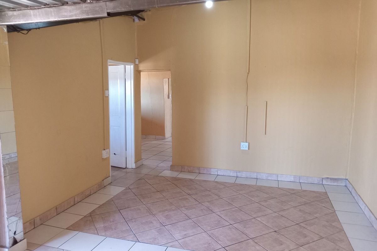 An empty living area featuring tiled flooring and exposed structural elements, offering a blank canvas for renovation and interior design updates.