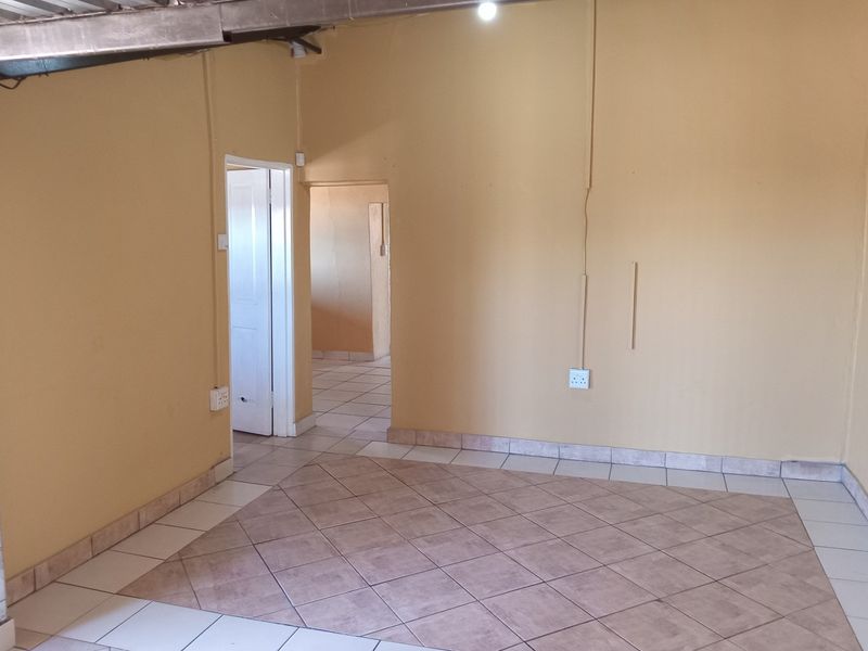 An empty living area featuring tiled flooring and exposed structural elements, offering a blank canvas for renovation and interior design updates.