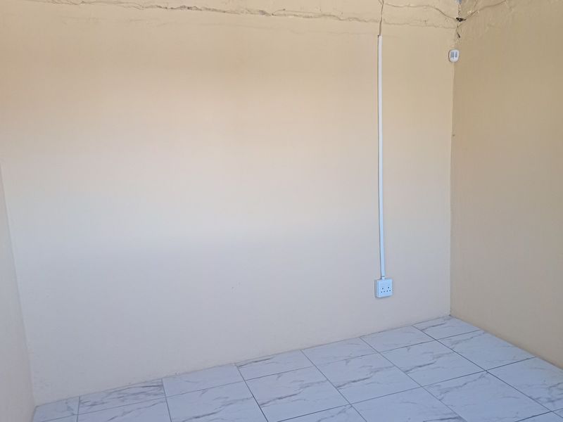 An empty bedroom featuring tiled flooring and visible surface-mounted electrical wiring, requiring cosmetic attention to the wall finishes.