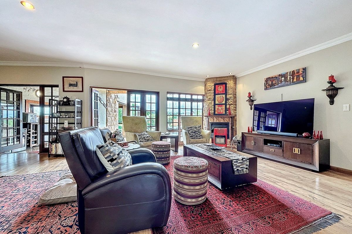 Spacious living room featuring a stone-clad fireplace, timber flooring, and large glass doors providing access to the outdoor patio area.