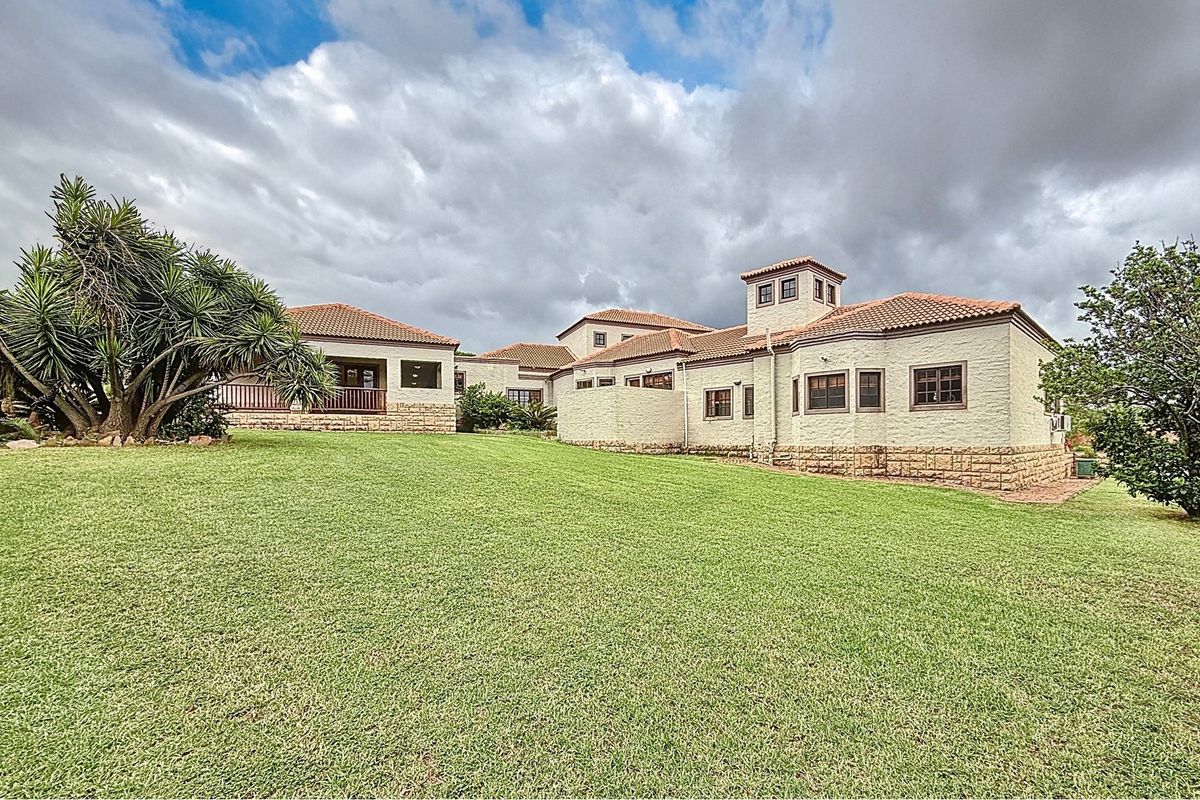 A view of the rear elevation of the house, featuring a large manicured lawn and traditional tiled roof architecture.