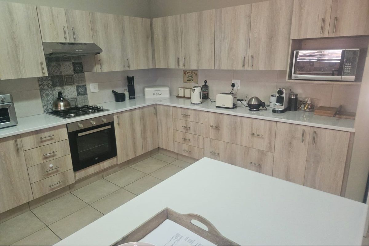 Modern kitchen featuring light wood-grain cabinetry, stone countertops, a built-in oven, gas hob, extractor fan, and a built-in microwave.