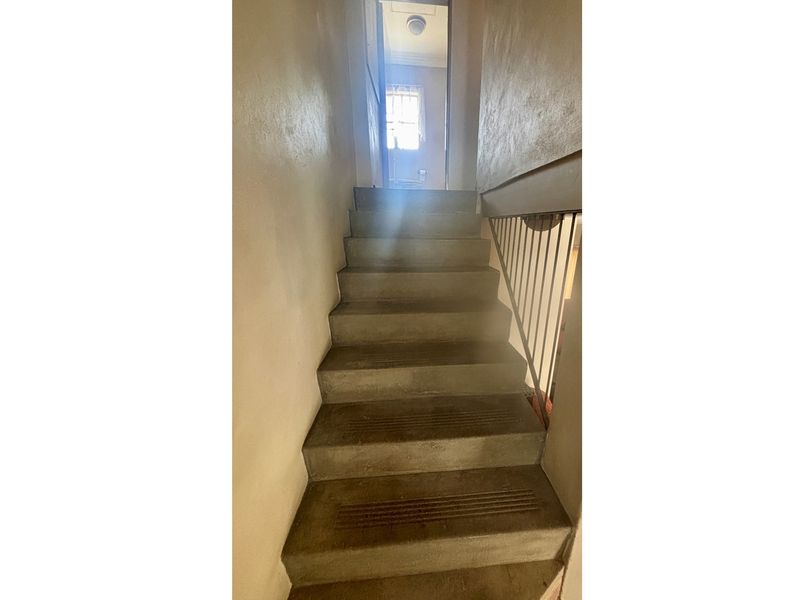 A functional staircase with concrete steps and a simple metal railing, providing access between levels within the townhouse.