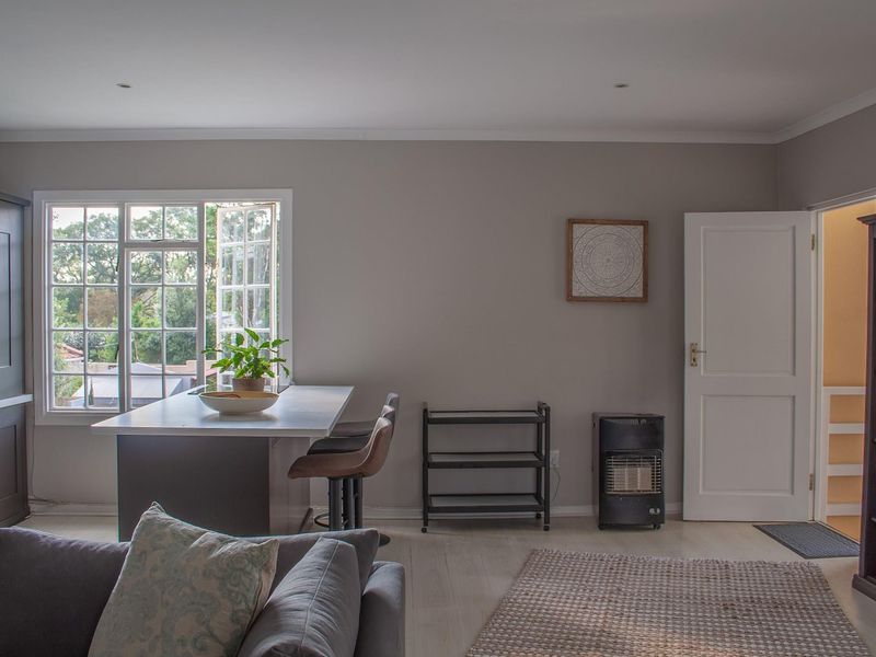 An open-plan living and kitchen area featuring modern cabinetry, a central island, and large windows providing natural light.