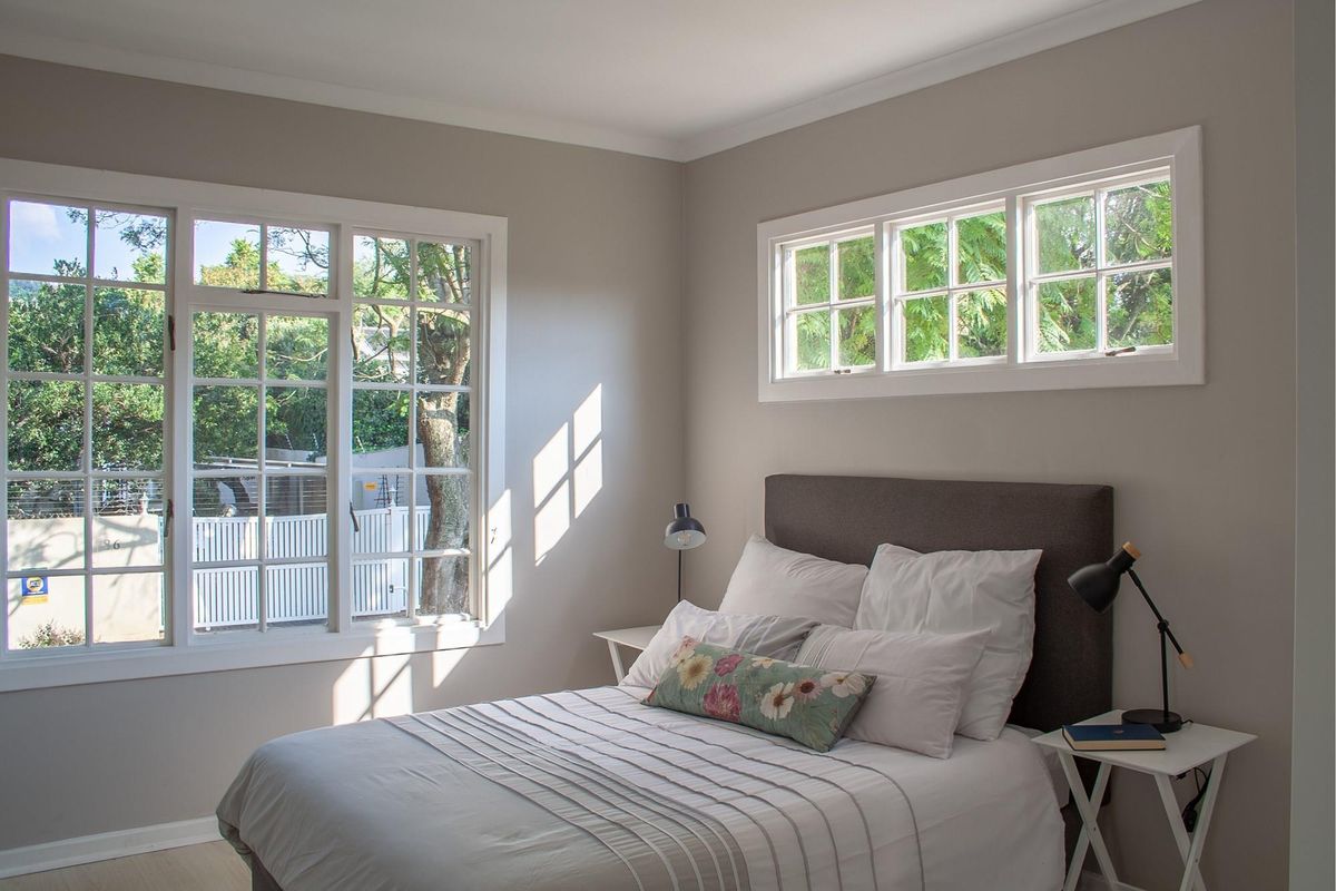 A bright and well-maintained bedroom featuring neutral wall tones, multi-pane windows, and classic coving detail.
