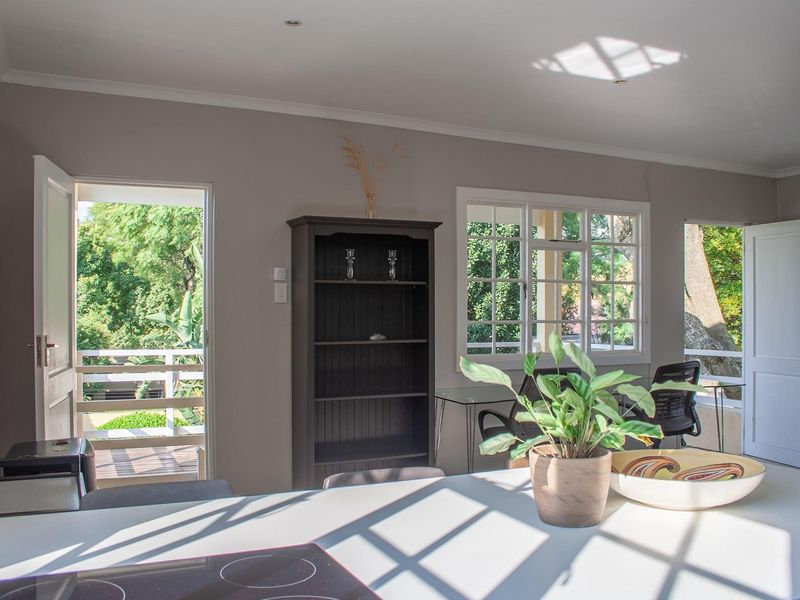 Bright open-plan living area featuring a built-in hob, multi-pane windows, and direct access to an outdoor balcony space.