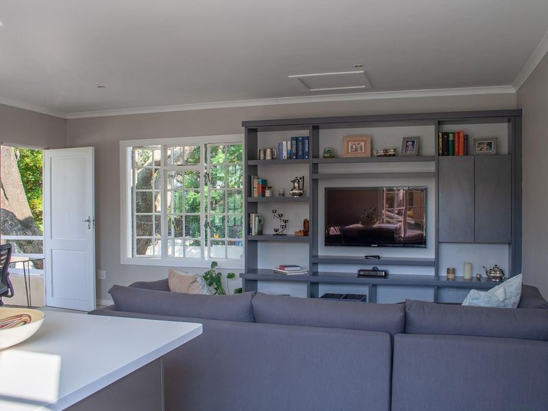 A well-maintained living room featuring a large built-in media and shelving unit, neutral wall tones, and natural light through a multi-pane window.