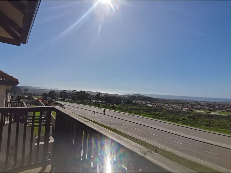 A scenic elevated view overlooking a coastal road and surrounding landscape from a balcony.