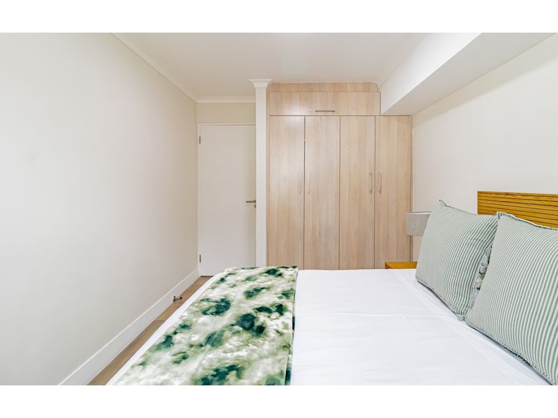 A well-maintained bedroom featuring built-in light wood cabinetry and neutral finishes, providing a clean and functional living space.