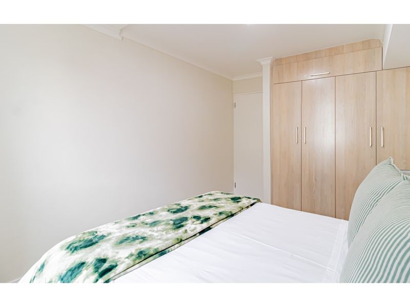 A well-maintained bedroom featuring light wood-toned built-in cabinetry and neutral wall finishes.