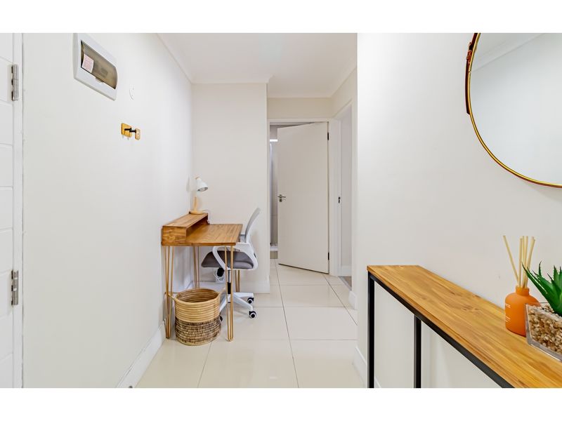 A bright, tiled hallway featuring a built-in electrical distribution board and access to adjacent rooms.