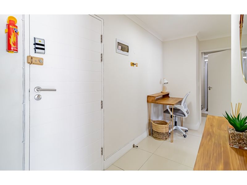 A bright entrance hallway featuring tiled flooring, a secure front door with deadbolt, and access to adjacent rooms.