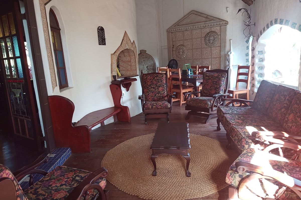 A rustic living room featuring hardwood floors, arched windows, and unique decorative wall reliefs, offering a distinct character with potential for modernization.
