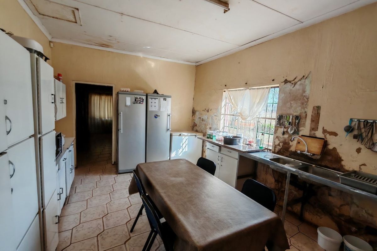 A dated kitchen area featuring basic cabinetry, a stainless steel sink, and significant wall and ceiling finish deterioration requiring renovation.