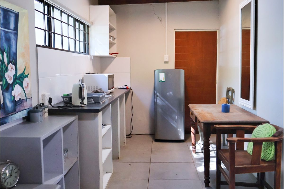 A compact kitchen area featuring tiled flooring, basic cabinetry, and a functional layout with direct access to an adjacent room.