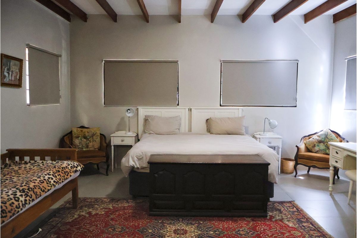 Spacious bedroom featuring exposed timber ceiling beams, neutral wall finishes, and roller blinds on the windows.