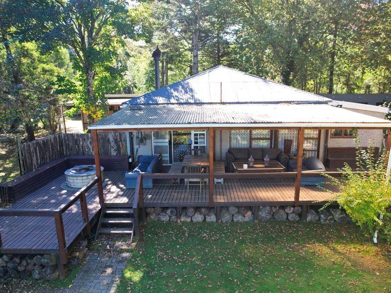 Elevated view of a rear timber deck featuring a built-in fire pit area, covered patio space, and direct access to the garden.