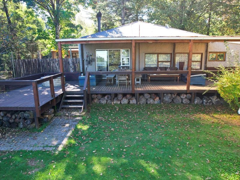 A spacious rear timber deck featuring a covered patio area, overlooking a private garden with mature trees and established landscaping.