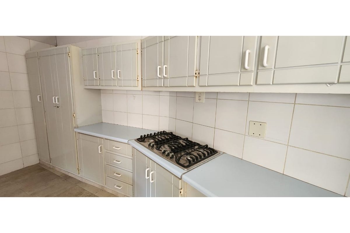 A functional kitchen area featuring built-in cabinetry, a tiled backsplash, and a fitted gas hob set into the countertop.