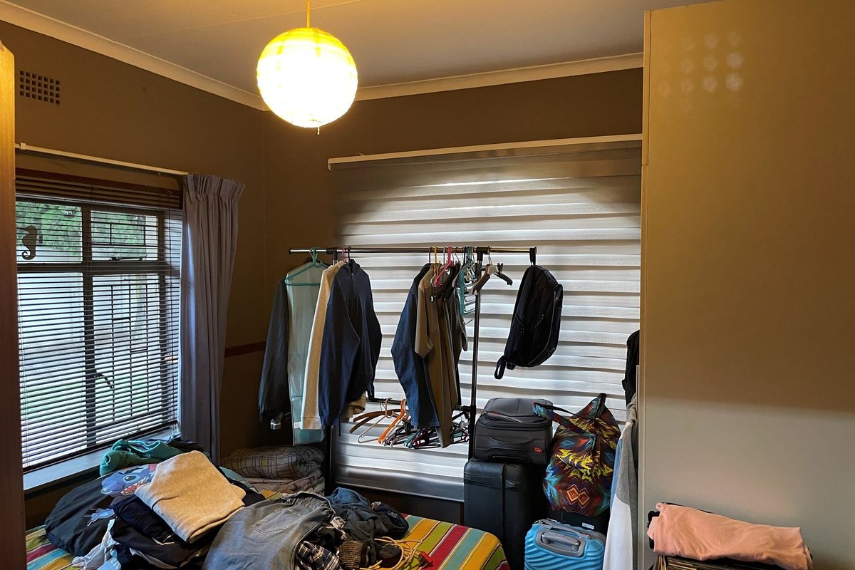 A bedroom featuring built-in cabinetry, horizontal window blinds, and a central pendant light fixture.